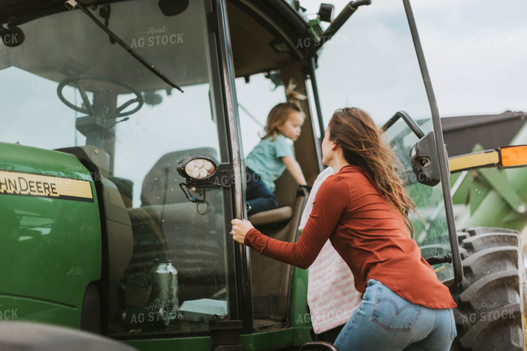 Female Farmer with Daugther Climbing into Tractor 8571