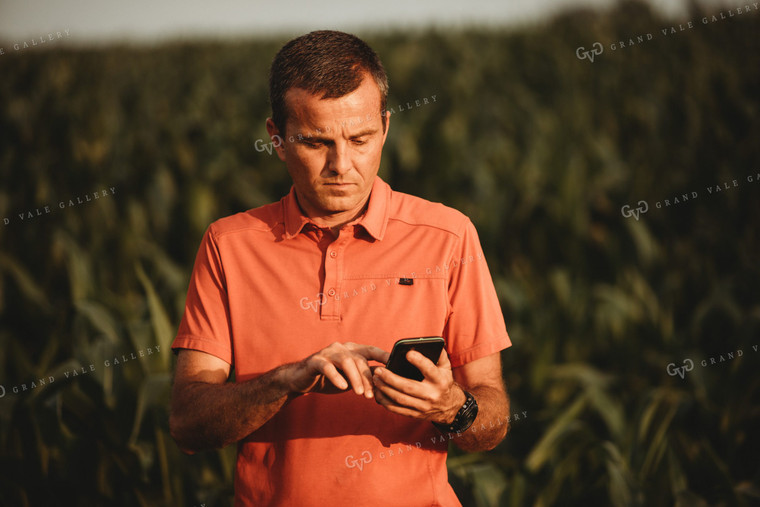 Farmer Looking at Phone next to Corn Field 4549