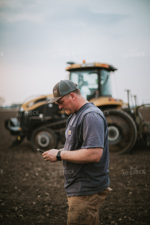 Farmer Looking at Phone in Field with Planter 5673