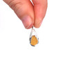 Amber Golden Sea Glass Lunar Drop Charm held to the light