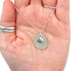 Seafoam Round Sea Glass and Sand Dollar Charm Necklace in hand for color references