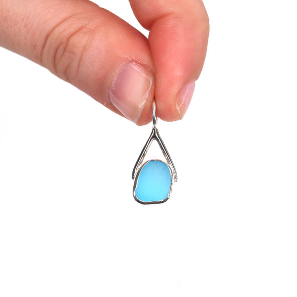 Turquoise Sea Glass Lunar Drop Charm held to the light