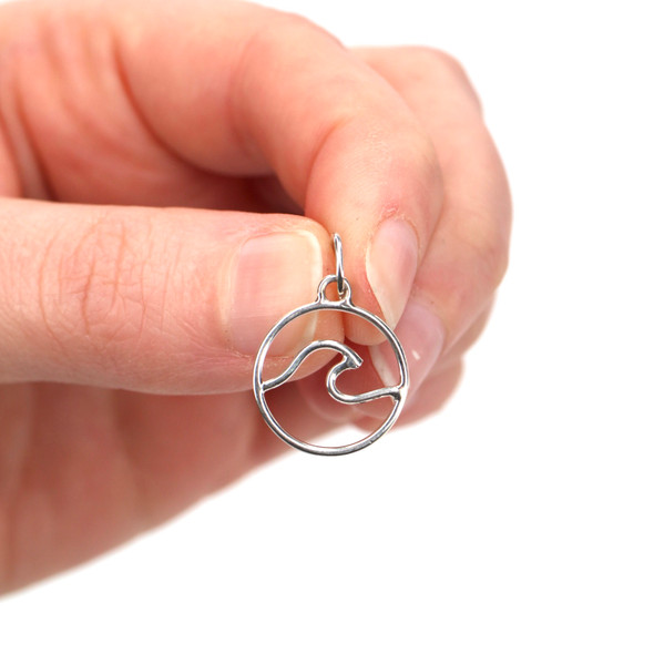 Sterling Silver Wave Charm held to the light