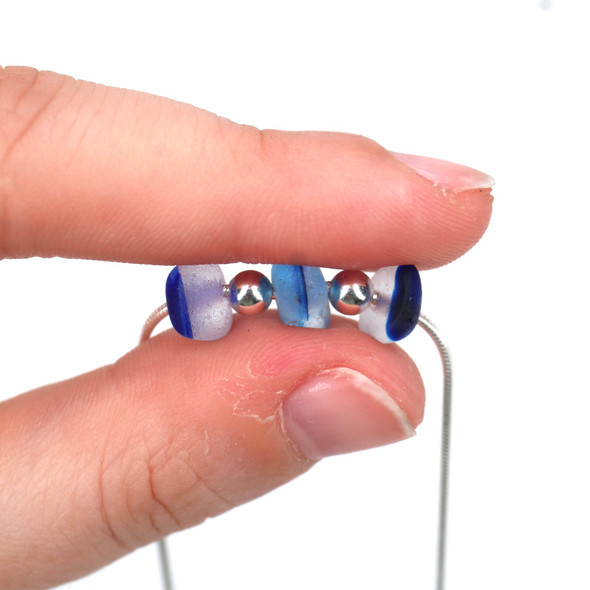 Blues Spotted Ultra Rare 3 Stone Necklace on Snake Chain held to the light