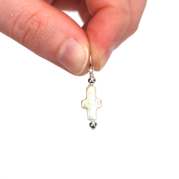 Pearl Cross Charm held to the light