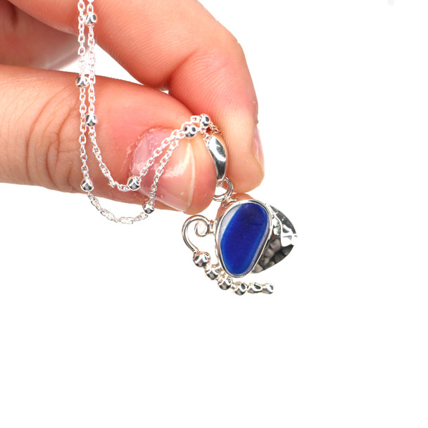 Blue Electric Spot Ultra Rare Sea Glass Mariposa Necklace held to the light