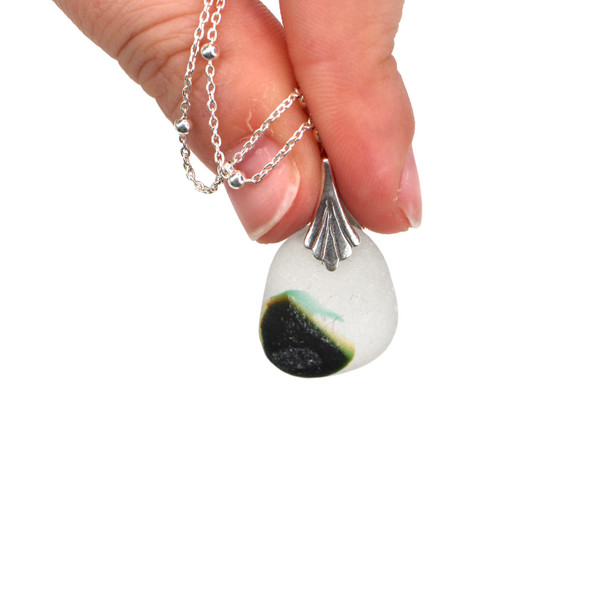 Green Mystic Swirl Ultra Rare Sea Glass Scallop Shell Necklace held to the light