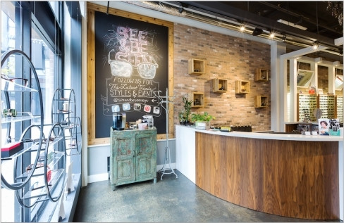 Optical showroom designed by CNS Frame Displays, with a curved reception desk and wall-mounted frame displays.