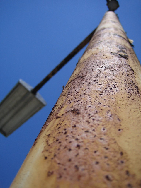 Steel light pole with rust on it.