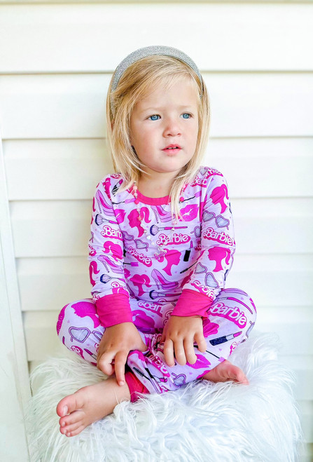 Pink long sleeve pink doll two piece pajamas for kids with all-over prints of pink doll icons, including hearts, sunglasses, lipstick, and silhouettes, made from soft bamboo fabric.