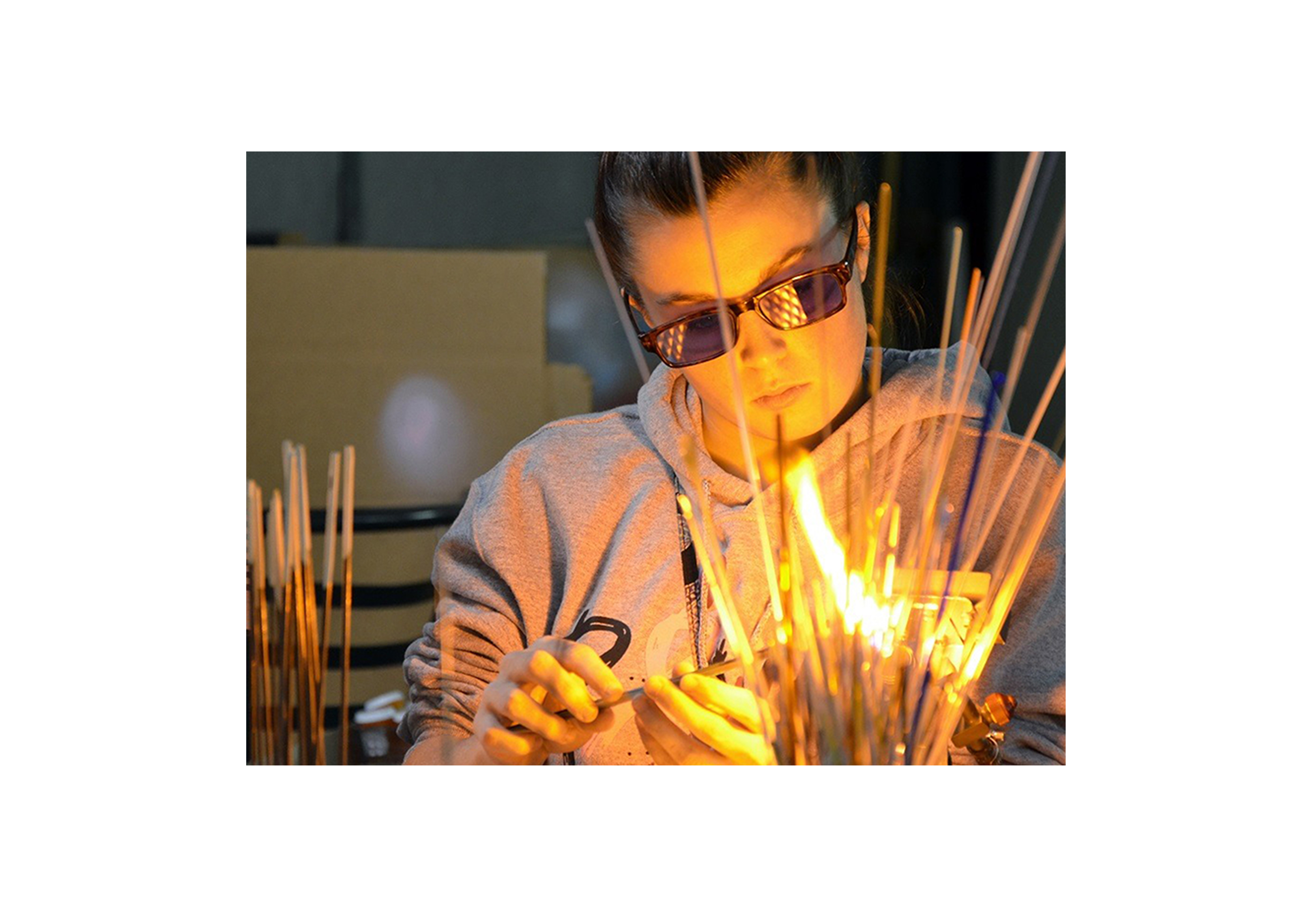 a young girl working on a glass bead with a torch