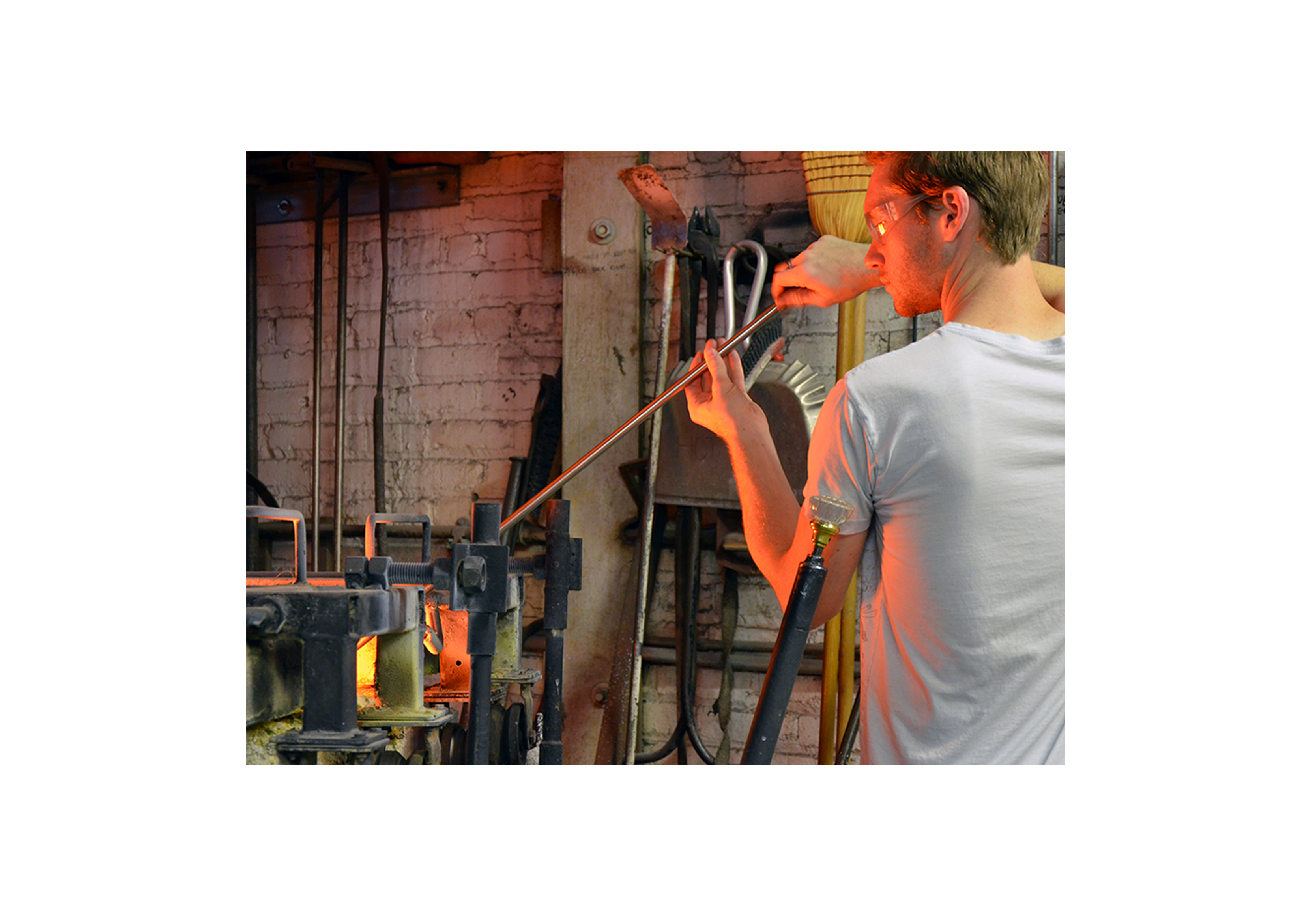 a young man working on a hot glass blown piece