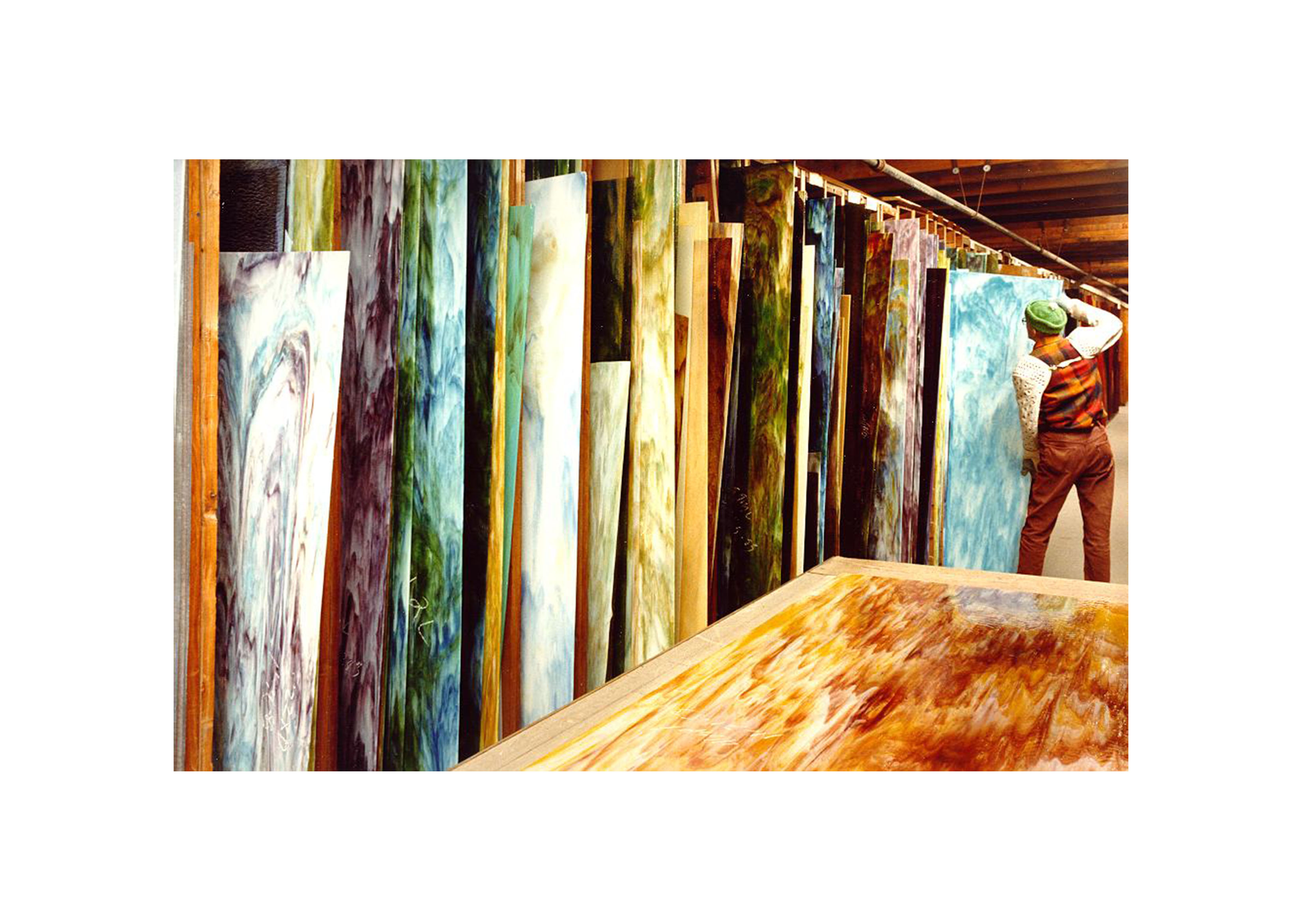 an image from the 1970's of a man pulling out a blue sheet of glass in the warehouse