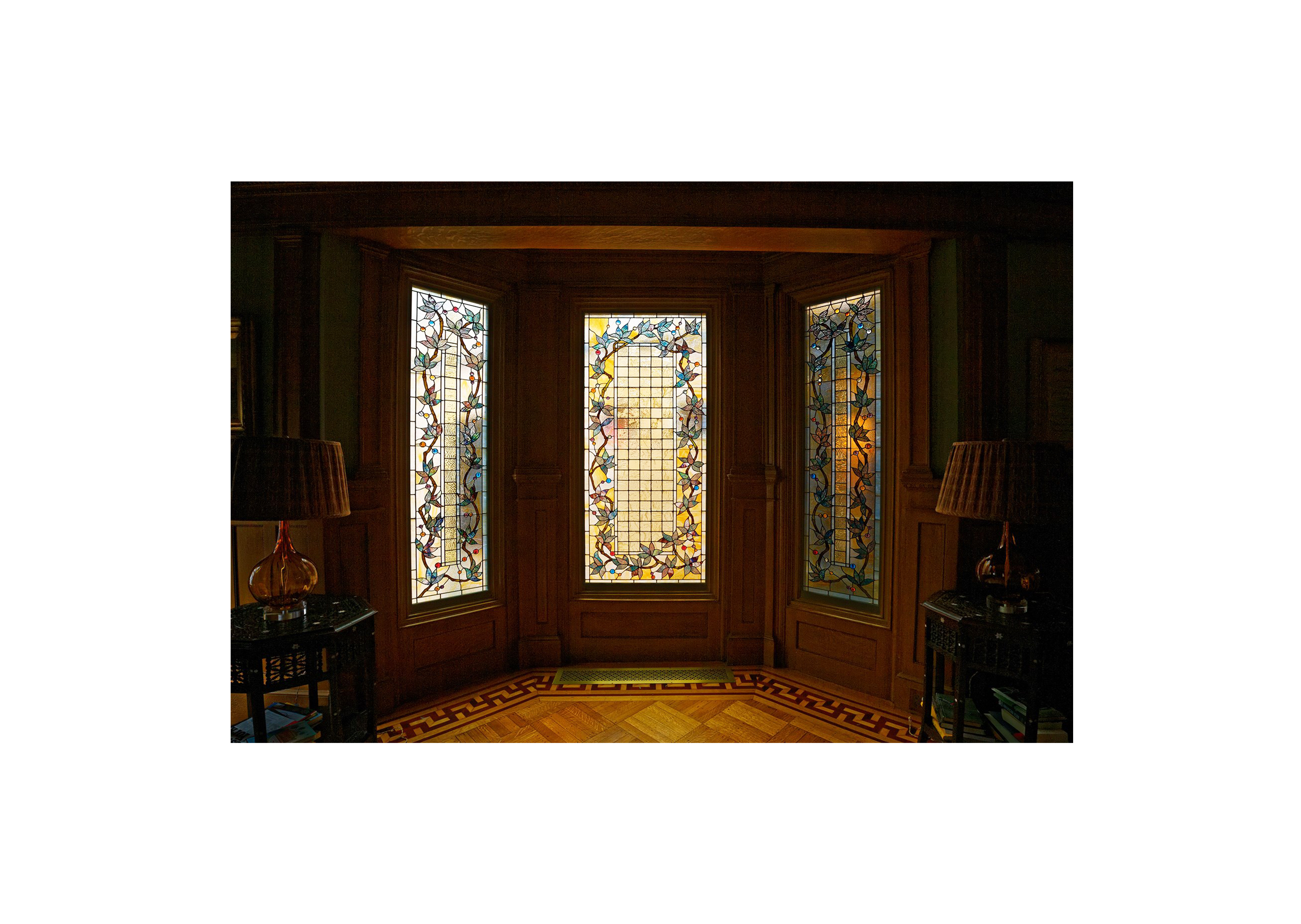 a dark wooden interior window with three stained glass panels
