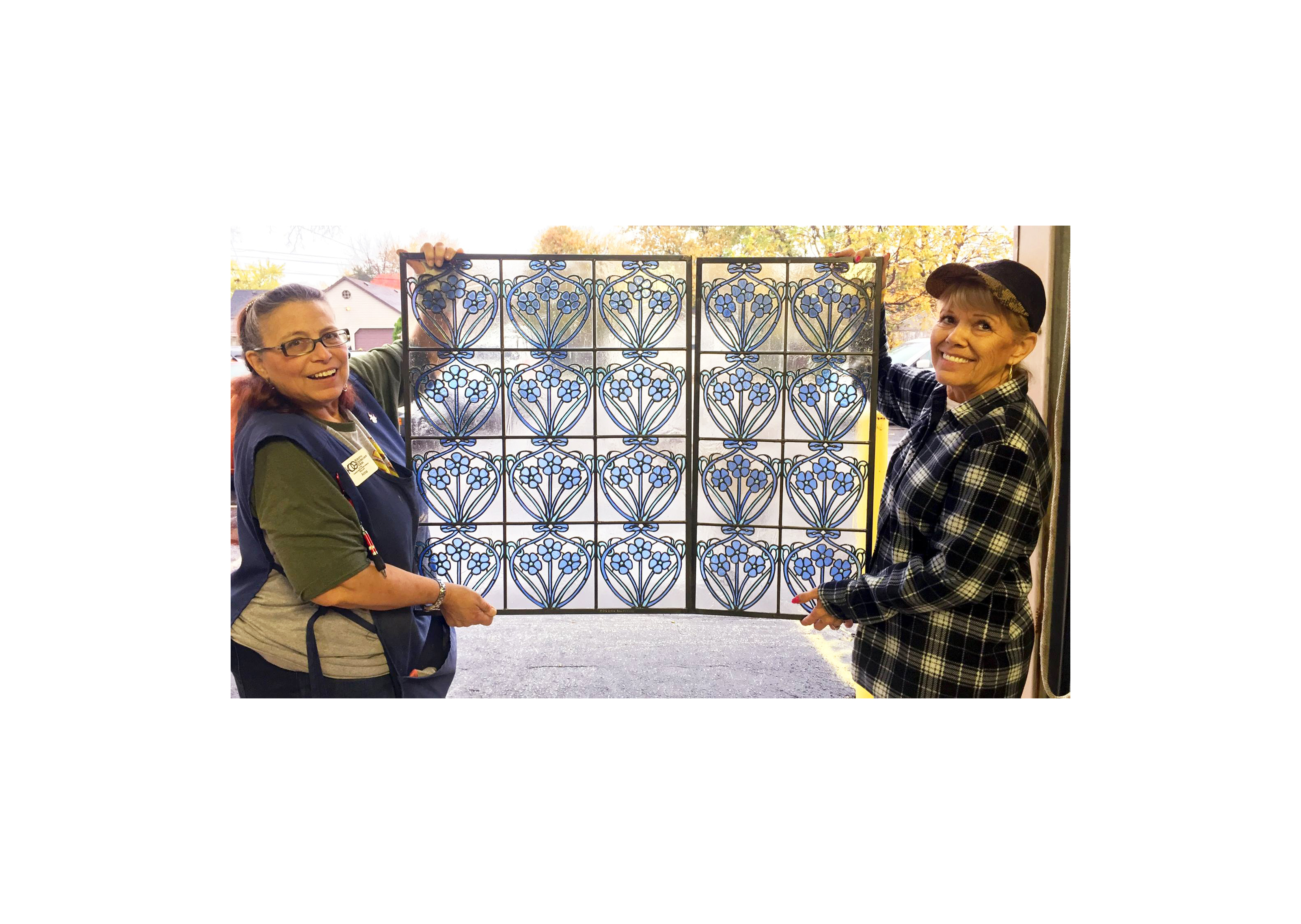 two women holding a blue floral pain of stained glass