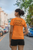 back  view  orange ildan  t-shirt  mockup  of  a  woman  standing  on  the  street with CHASE YOUR DREAMS