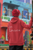 back  view  red gildan  hoodie  mockup  of  a  woman  with  a  turban  standing  in  a  street  with I AM A SURVIVOR