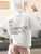 white back view hoodie mockup of a woman in a cozy outfit making a peace sign at home with BE A CHANGE AGENT!