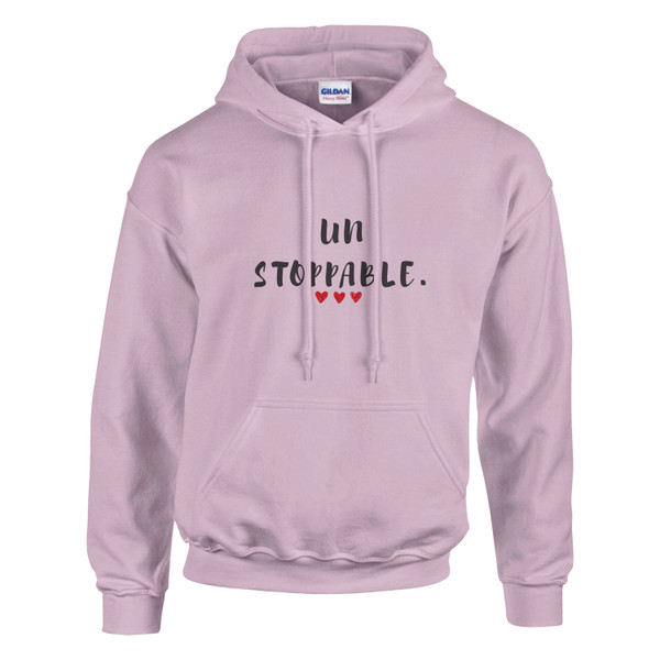 Front-facing product mockup of a light pink pullover hoodie displayed against a light gray background. The hoodie features a centered motivational design with the word “un” above the larger word “STOPPABLE.” in a distressed black hand-lettered font. Three small red hearts are positioned beneath the text. The hoodie includes a drawstring hood, long sleeves, ribbed cuffs and waistband, and a front kangaroo pocket. The design creates an uplifting, empowering message that conveys confidence, resilience, and determination.