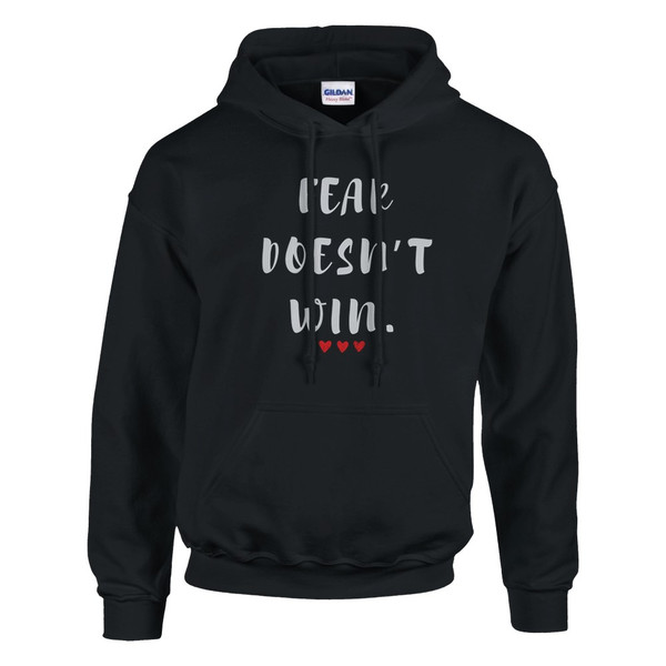 Black hoodie featuring the motivational quote “FEAR DOESN’T WIN” in white lettering with three red hearts, symbolizing courage, resilience, hope, empowerment, and overcoming fear.
