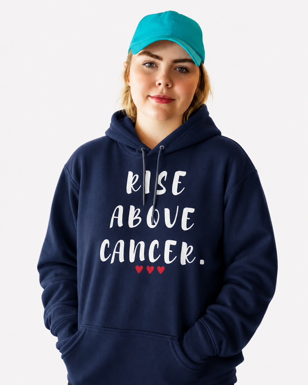 Woman wearing a black hoodie featuring the inspirational quote “Rise Above Cancer” with red heart accents, standing on a staircase, motivational apparel promoting hope, courage, resilience, strength, and cancer awareness.