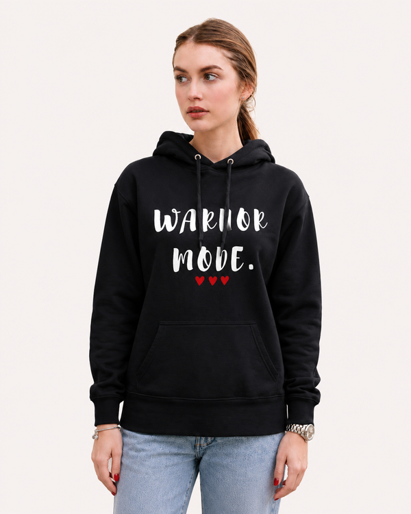 Woman wearing a black hoodie featuring the inspirational quote “Warrior Mode” with red heart accents, styled casually outdoors with a backpack, empowering motivational apparel for women.