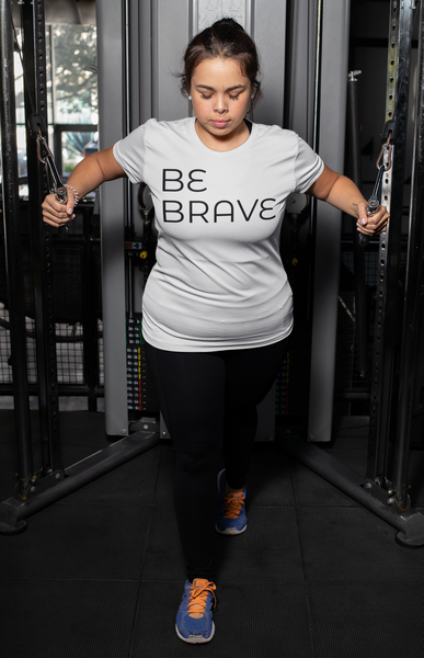 plus  size  white t -shirt  mockup  featuring  a  woman  doing  cable  extensions  at  a  gym with BE BRAVE
