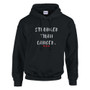 Black pullover hoodie displayed against a light gray background. The front features the motivational cancer-awareness message “STRONGER THAN CANCER.” in distressed white lettering, accented by three small red hearts beneath the text. The hoodie includes a drawstring hood, kangaroo pocket, and ribbed cuffs and hem. The design conveys strength, resilience, hope, and support for those affected by cancer.