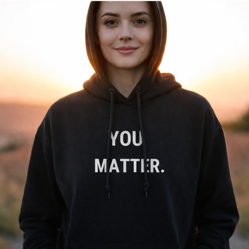 Young woman with black hoodie covering her head, sunsent behind her, YOU MATTER. inspiration quote