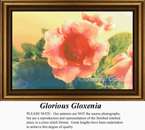A soft, velvety pink gloxinia flower with lush green leaves fills the frame, ready for your next cross stitch project on aida cloth.