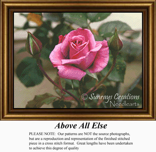 A pink rose at the center, surrounded by unopened buds and green leaves, displayed as a counted cross stitch chart.