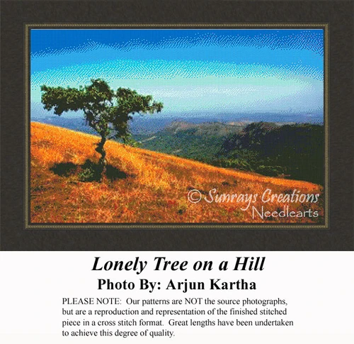A solitary tree stands on a grassy slope, overlooking mountains in the distance, rendered as a cross stitch design with autumn hues.