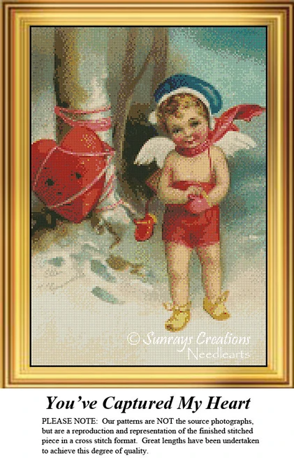 A cherub with a blue cap and red outfit stands beside a large heart, holding a small heart in a wintry scene, available as a printable pattern.