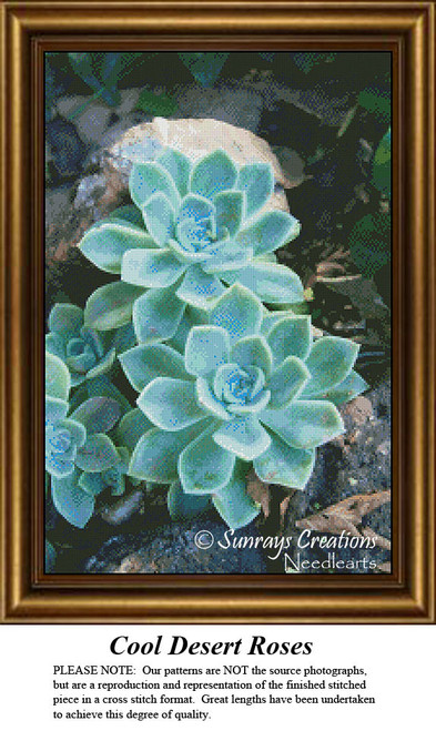 A trio of desert roses sits among rocky terrain, frozen in time as a counted cross stitch pattern.