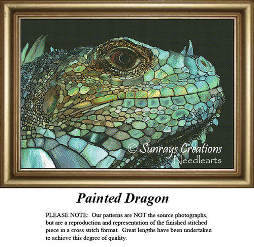 A detailed, textured lizard with vibrant scales in blues, greens, and gold, shown as a counted cross stitch design, framed elegantly.