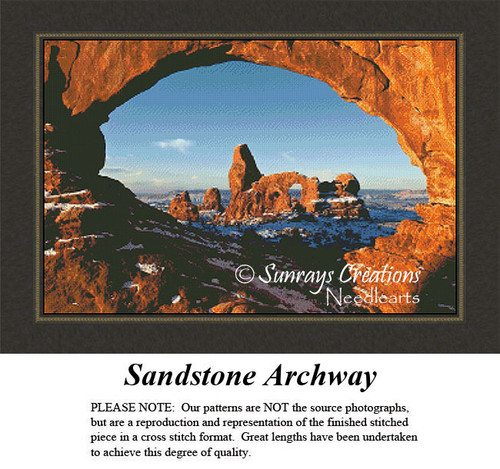 A sandstone archway framed by rocky cliffs, with varying shades of brown and blue sky in the background; a downloadable pattern for cross stitch.