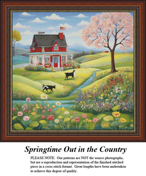 A quaint farmhouse sits on rolling green hills, with a pink tree nearby and two cows grazing, yours as a counted cross stitch kit.
