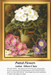 A cross stitch chart of potted primroses in pink, violet, and white, designed by Oliver Clare, with lush green leaves surrounding the flowers.