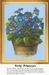 A pot filled with cheerful blue primroses with yellow centers sits against a light background, presented as a cross stitch chart ready for stitching.