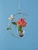Crescent hanging rooting vase with Brass Butterfly accent and handblown glass vase with flower stems in water on a blue background