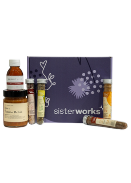 An overhead view of the open SisterWorks Spice Enthusiast's Delight Hamper. The hamper contains a collection of gourmet spices, including Hot Chilli Oil, Smoky Herb Seasoning, Zesty Spice Blend, Herbal Lemon Mix, and Spicy Fusion Salt. The items are arranged in a box, highlighting a beautiful gift set for anyone who loves to cook.