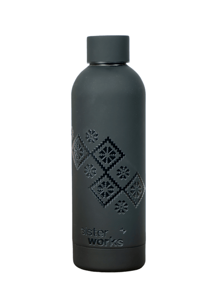 Front view of the black 'Embroidered Roots' reusable bottle by SisterWorks against a plain green background. The intricate 'Embroidered Roots' pattern, designed by Fernanda Rodriguez, is clearly visible on the bottle's surface, highlighting its unique artistic and sustainable design.