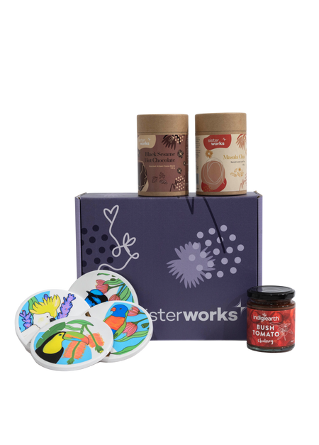 Front view of the SisterWorks Cultural Fusion Hamper contents laid out. Includes SisterWorks Black Sesame Hot Chocolate, Masala Chai, bush tomato chutney, and four colourful Cultural Fusion Coasters by artist Marynel Jaimes. The vibrant purple standard gift box is visible, showcasing a thoughtful, ethically sourced cultural gift.