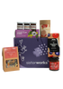 An overhead view of the open SisterWorks Foodie Hamper. The contents are neatly arranged in a box, including a jar of Eggplant Pickle, a 3-pack of ShortHive Infused Honey, a pouch of Cinnamon Myrtle Black Tea, a bag of Salty n' Crunchy Mix, and a box of Kakadu Plum Co. Crackers. The collection highlights a perfect gourmet gift set for a foodie