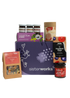 A SisterWorks Aussie Holiday Hamper. The box contains STREAT Gingerbread Stars, SisterWorks Raspberry Jam, BSKT Davidson Plum Vegan Chocolate, SisterWorks Lemon Myrtle Green Tea, and Australian Icon Coasters. The items are arranged neatly in a box, highlighting a festive and ethical gift set.