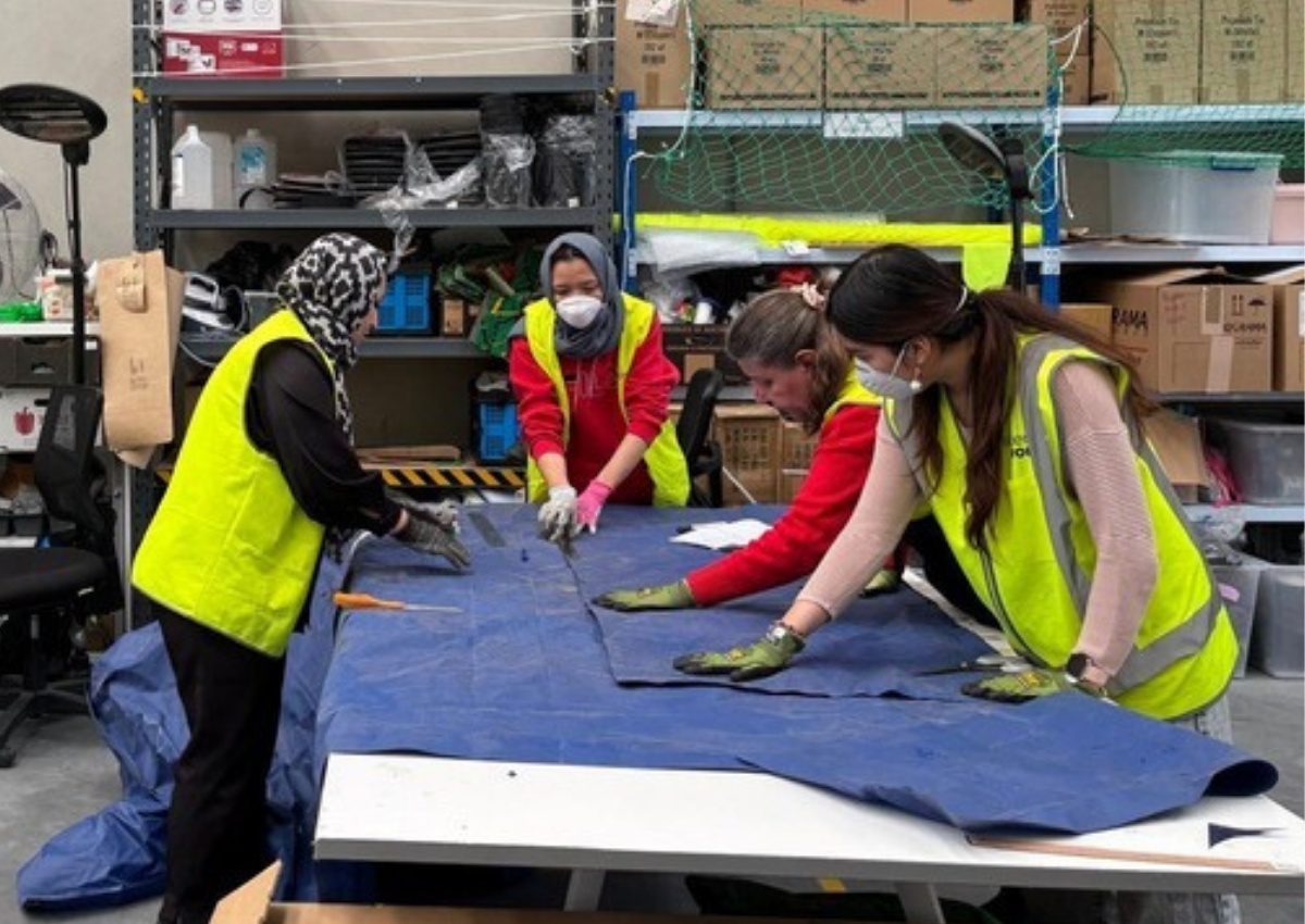 SisterWorks team preparing tarpaulin material for production