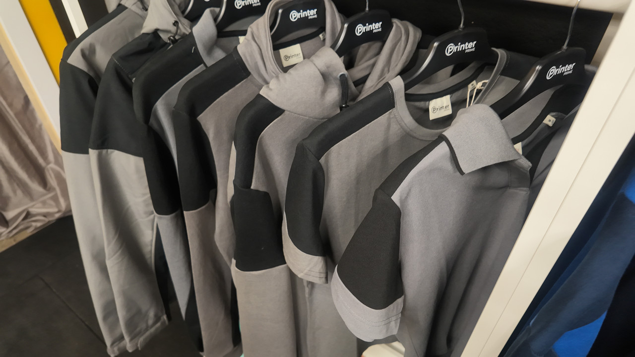 Workwear hanging on a rail in good condition — hoodies, sweatshirts and polos in grey and black