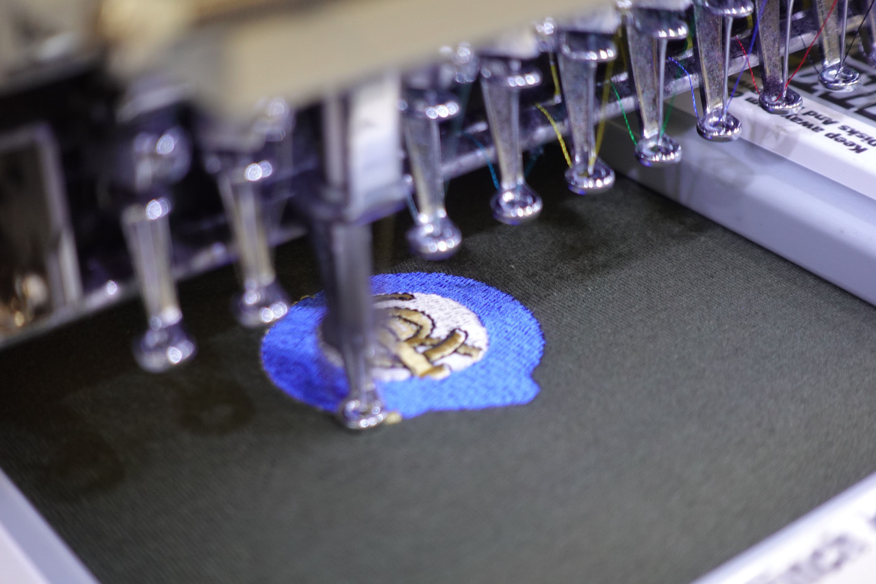 Close-up of an embroidered logo, showing the raised texture and depth of the thread stitched into the fabric