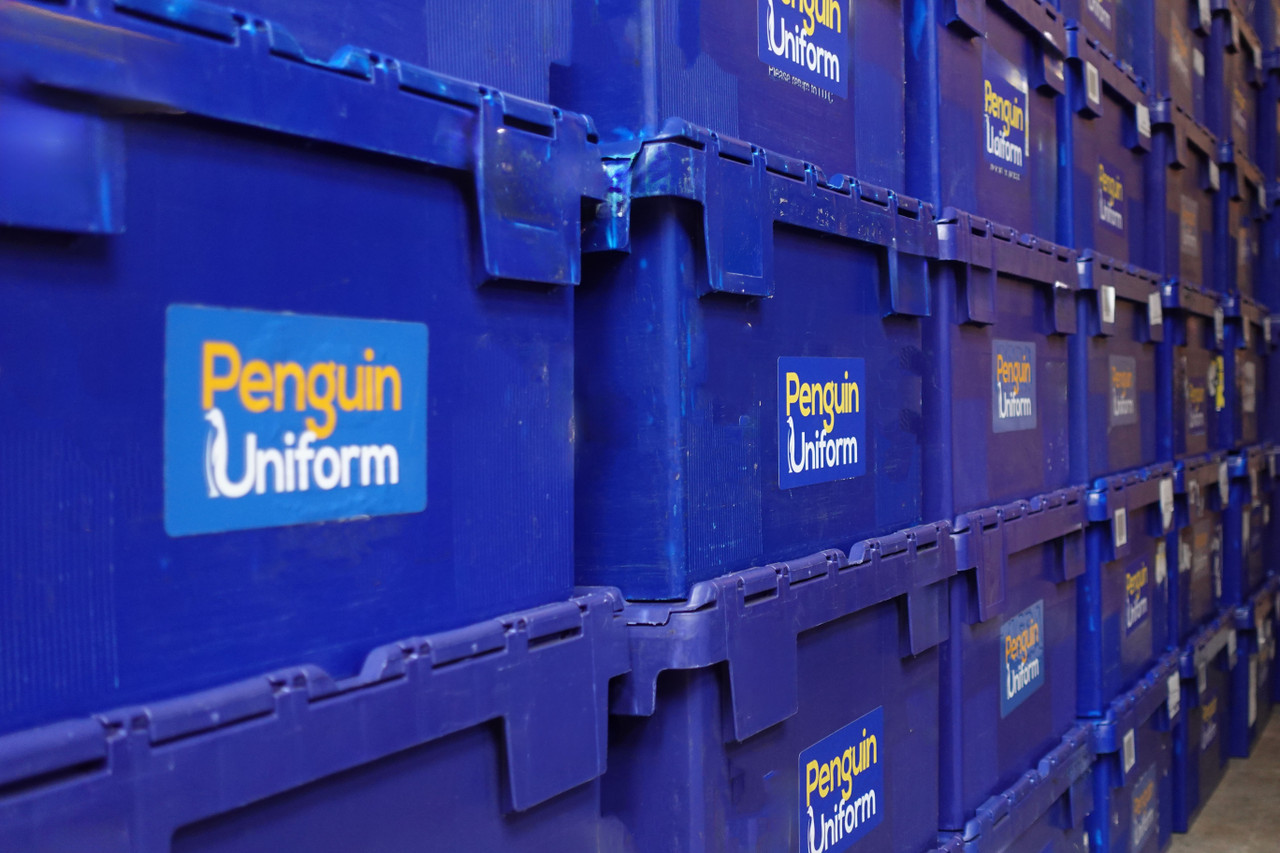 Rows of blue Penguin Uniform job boxes stacked and filed in the warehouse, each order boxed and sequenced