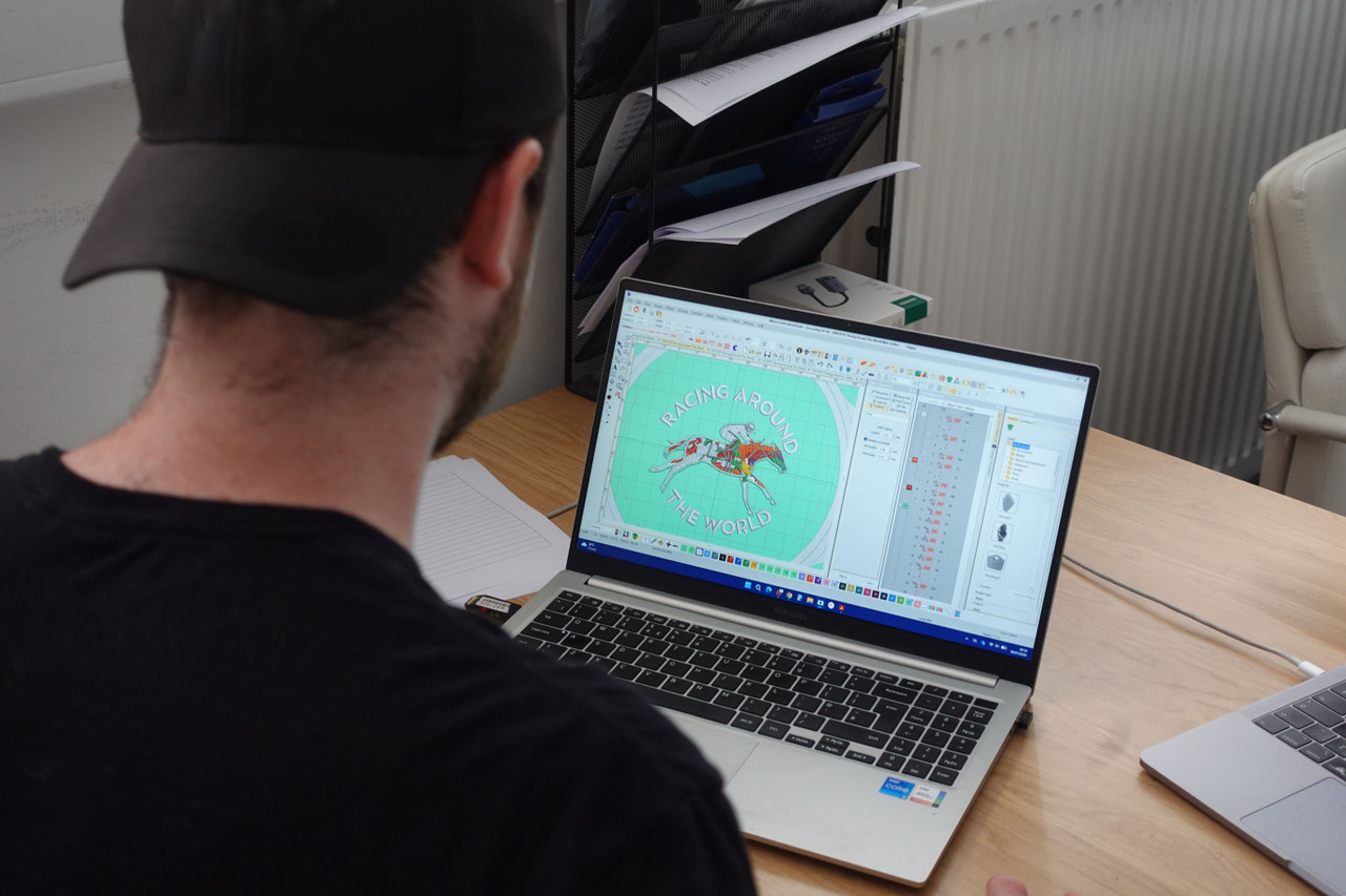A member of the team at a laptop reviewing a digitised embroidery design in specialist software before it goes to the machines
